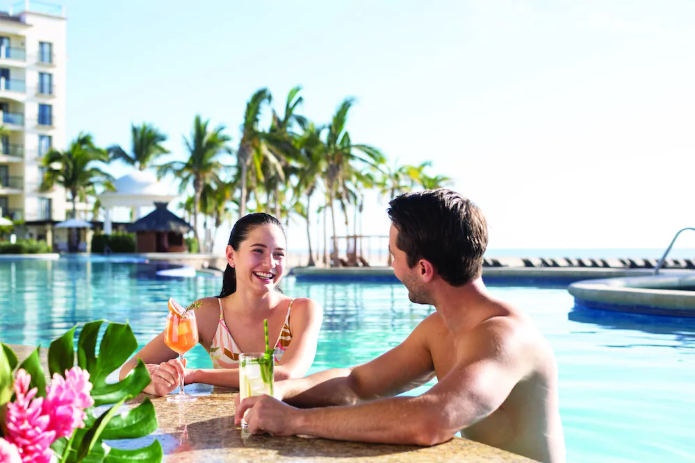 man and woman enjoying cocktails in the pool